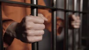 Person in prison holding cell bars