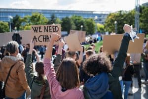 Large group at a protest with raised hands and signs